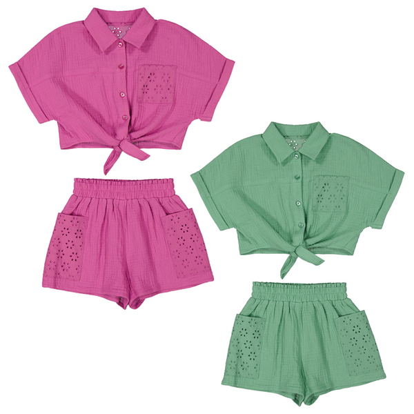 Two girls’ summer short sets are displayed. Each set includes a short-sleeved, button-up top with a front tie and matching high-waisted shorts. Both the tops and shorts have eyelet lace pockets for a feminine touch. One set is bright pink, and the other is a soft sage green. The fabric has a light, gauzy texture, ideal for warm weather.