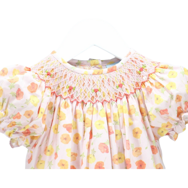 Detailed close-up of pink and orange hand-smocked neckline with embroidered flowers on floral print fabric.


