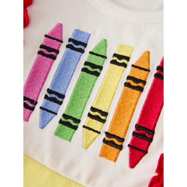 Close-up of colorful embroidered crayons on white bodice of girls' school dress, framed by red ruffles.

