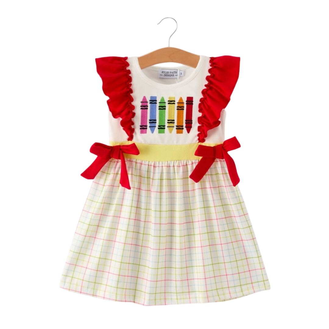 Front view of girls’ school dress with red ruffle sleeves, yellow waistband, plaid skirt, and colorful crayon embroidery.