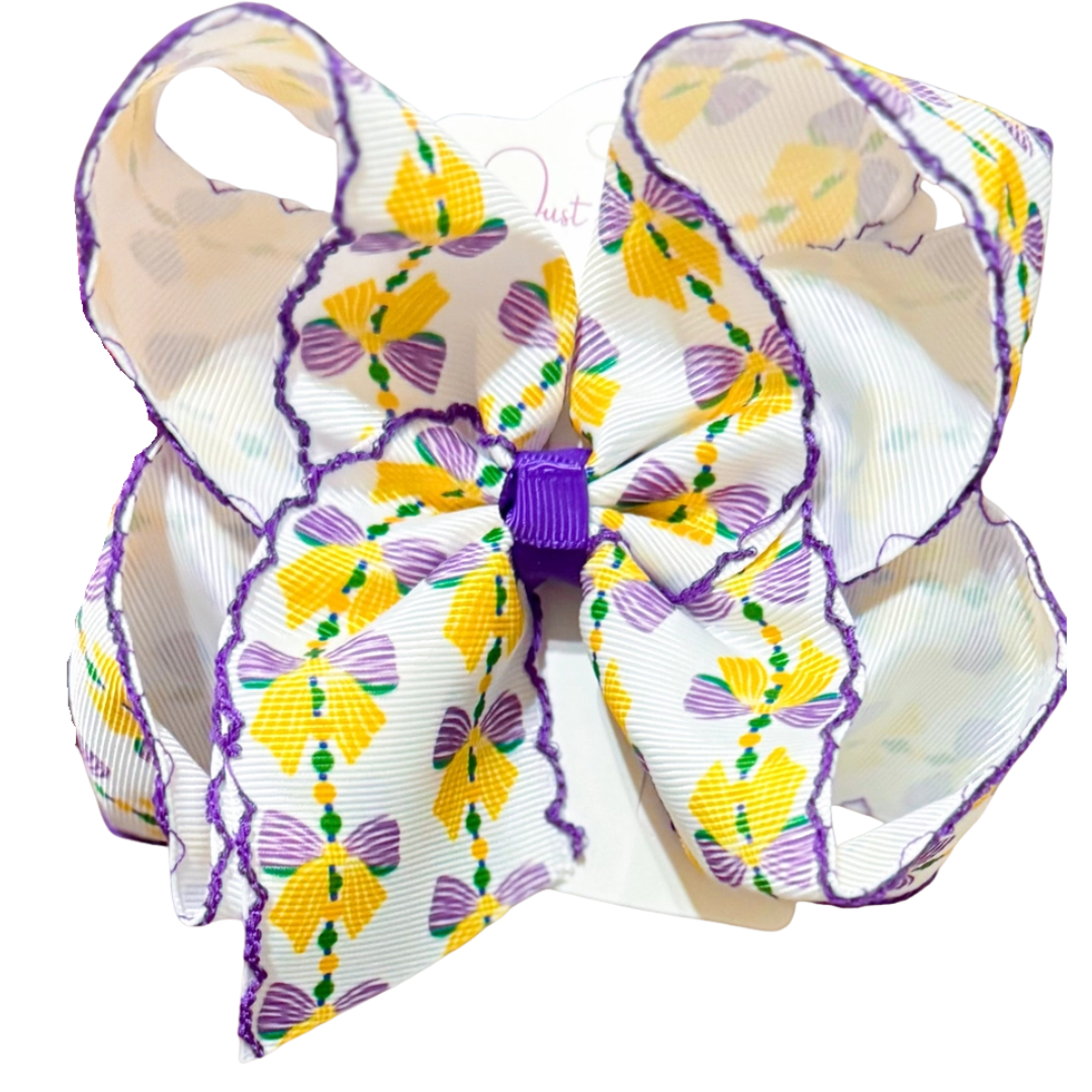 Large Mardi Gras hair bow with purple moonstitch trim and a bead-and-bow print in purple, gold, and green.