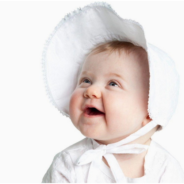 Smiling baby wearing a classic white eyelet bonnet with a wide brim and chin tie.