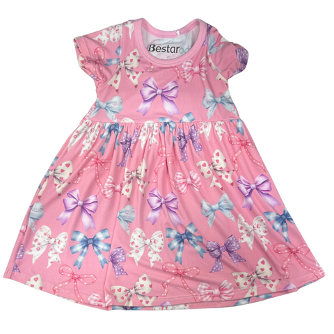 Pink short-sleeve dress with colorful all-over bow print in various patterns, featuring a gathered waist and full skirt.