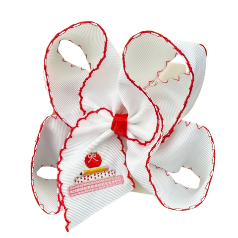 White grosgrain hair bow with red scalloped edges and embroidery of stacked books topped with a red apple on the bow tail.