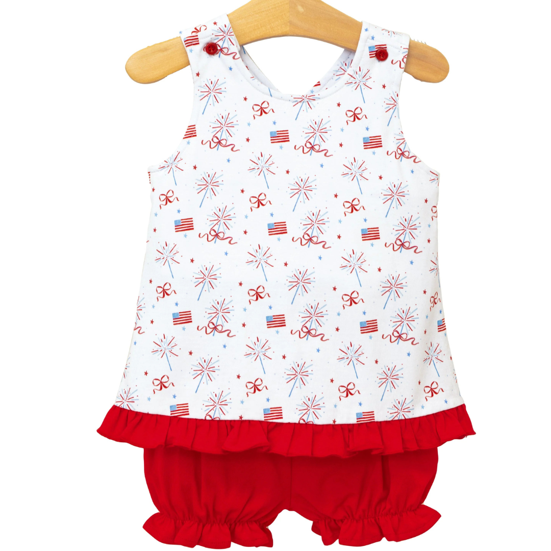 white shirt with american flags, bows, and fireworks with a red ruffle bottom and a crisscross back. is sleeveless and has matching red ruffle bloomers. 