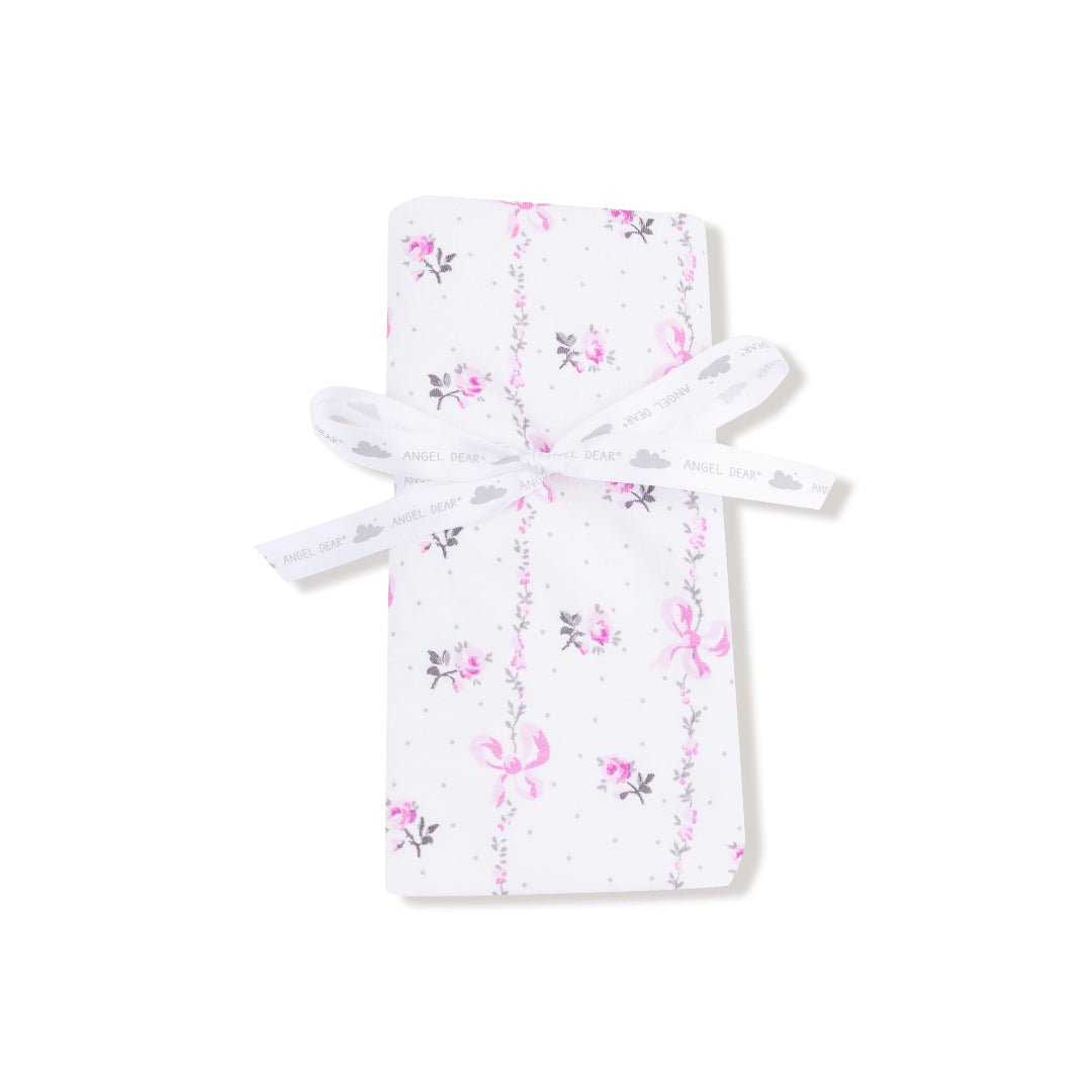 Baby blanket with soft pink interior and floral bow-printed exterior, finished with matching pink ruffle trim