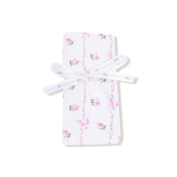 Baby blanket with soft pink interior and floral bow-printed exterior, finished with matching pink ruffle trim