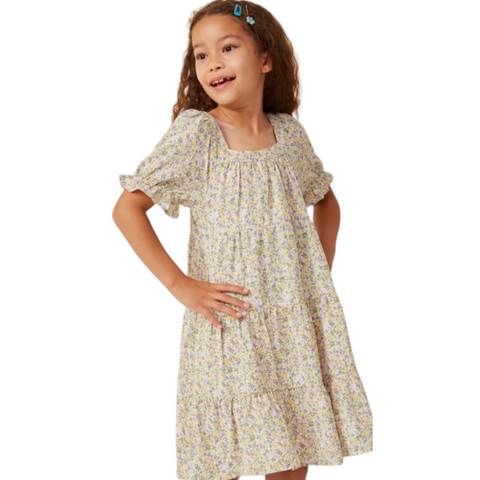 Girl wearing coral ditsy floral dress with ruffle sleeves and back keyhole button closure, hair down.