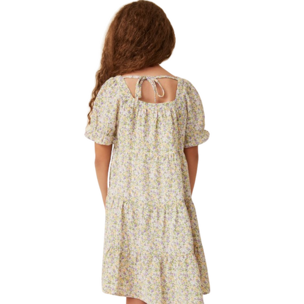 Girl smiling in coral floral A-line dress with flutter ruffle sleeves and gathered yoke neckline