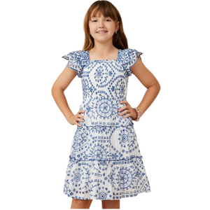 Girl wearing a white dress with blue embroidered patterns, scalloped flutter sleeves, and a square neckline.