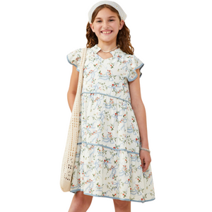 Girl facing forward wearing white floral dress with blue ribbon print and flutter sleeves