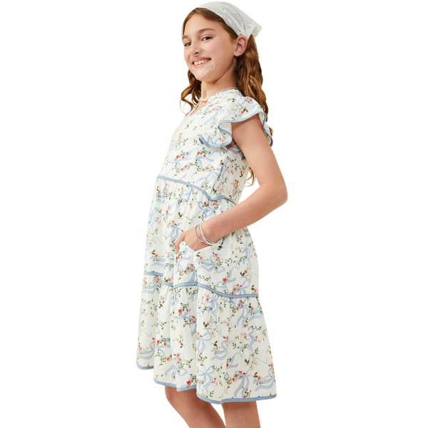 Side view of girl showing tiered floral dress with pockets and blue trim