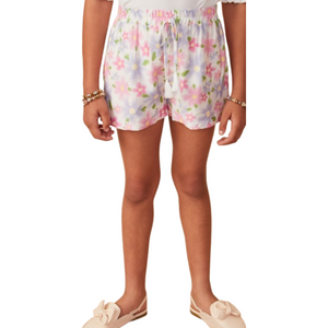 Girl wearing pastel floral pull-on shorts with tassel drawstring and pockets, paired with neutral slip-on shoes
