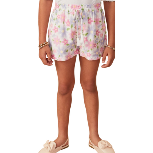 Girl wearing pastel floral pull-on shorts with tassel drawstring and pockets, paired with neutral slip-on shoes