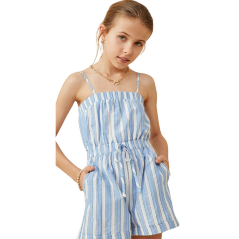 Girl wearing a blue and white striped romper with thin straps, tie waist, and side pockets, looking confidently at the camera.
