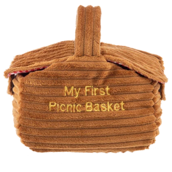 Soft brown plush picnic basket with textured corduroy fabric, carry handle, and embroidered “My First Picnic Basket” lettering.