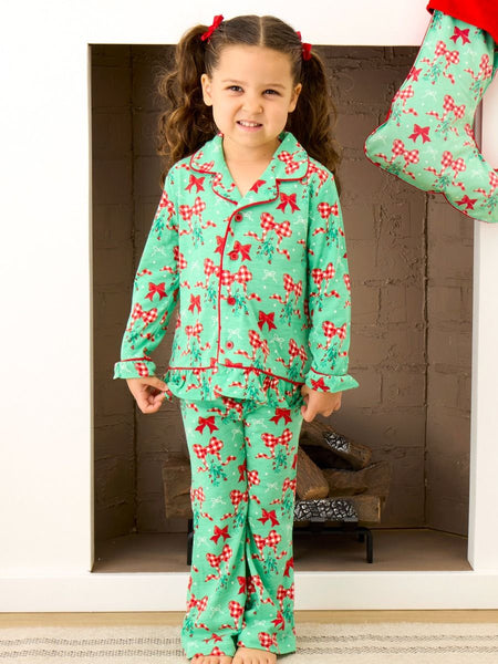 A little girl modeling the Mistlebows ruffle green pajama set. 