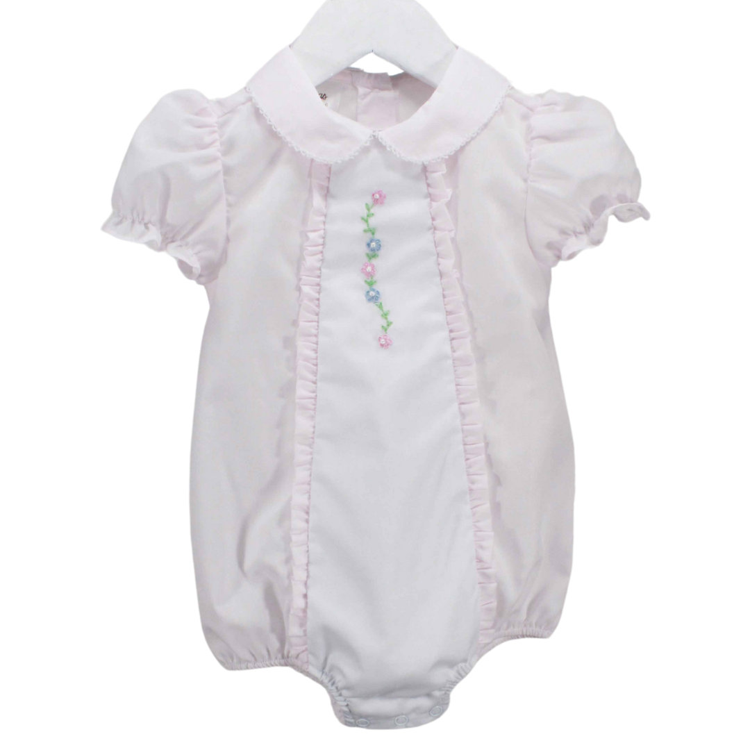 light pink baby girl bubble with a Pink baby bubble with a white center insert, pink ruffles along the sides, a delicate picot stitch on the collar, and puff sleeves. The center bodice features a hand-embroidered floral accent.