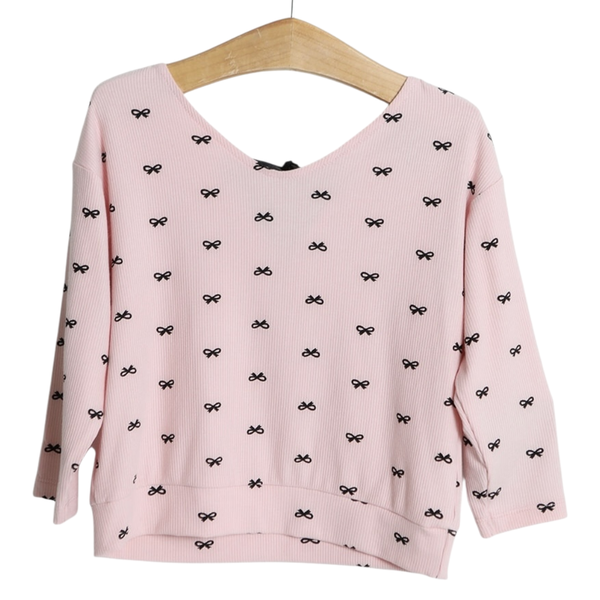 Girls pink ribbed sweatshirt with small black bow print and long sleeves on hanger