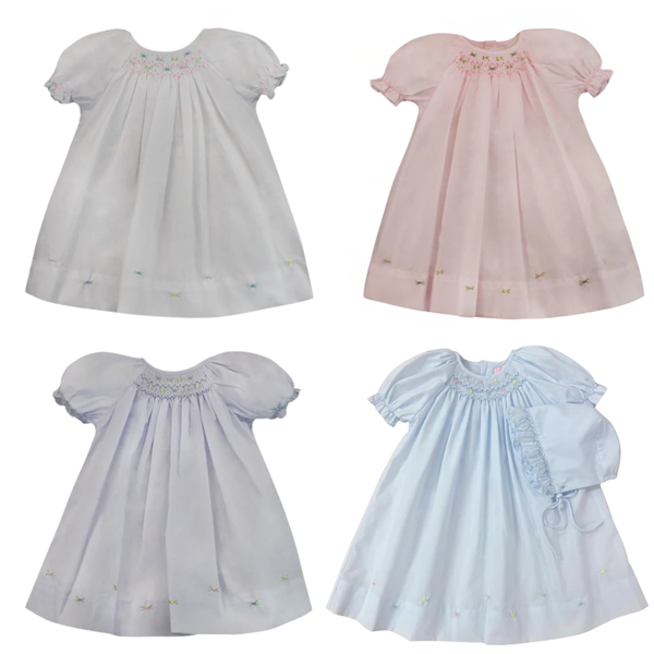 Four baby dresses in different colors on a white background