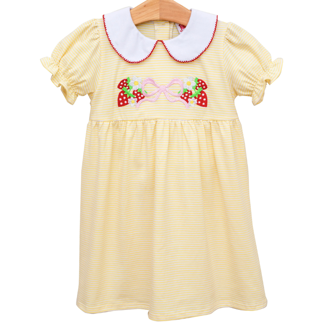 yellow dress with a white collar and red trim. has strawberries, daisies, and a pink bow on the front. 
