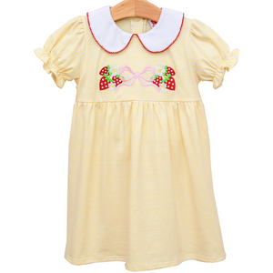 yellow dress with a white collar and red trim. has strawberries, daisies, and a pink bow on the front. 