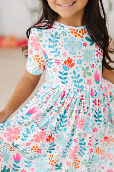 soft flowy twirl dress with bright floral print in blues, pinks and greens.