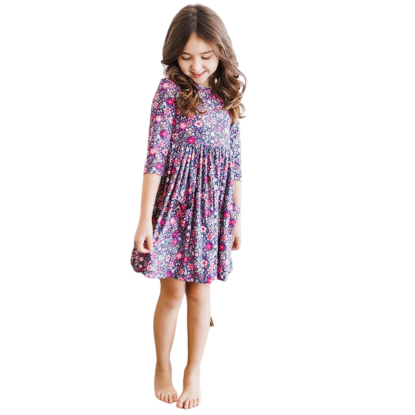 Girl modeling a navy floral twirl dress with bright pink flowers, a classic empire waist, and soft stretchy fabric perfect for everyday wear.